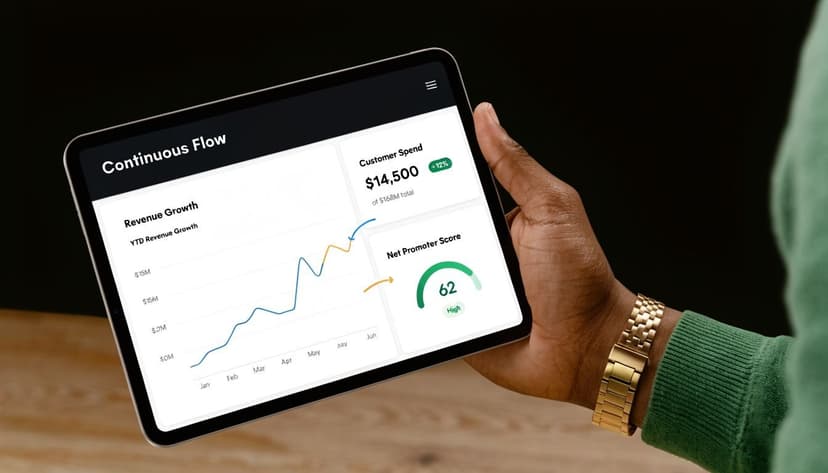 A person holding a tablet displaying a business dashboard with revenue growth and customer spend metrics.